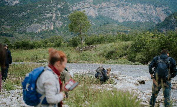 Participants on a nature walk recording species by a river
